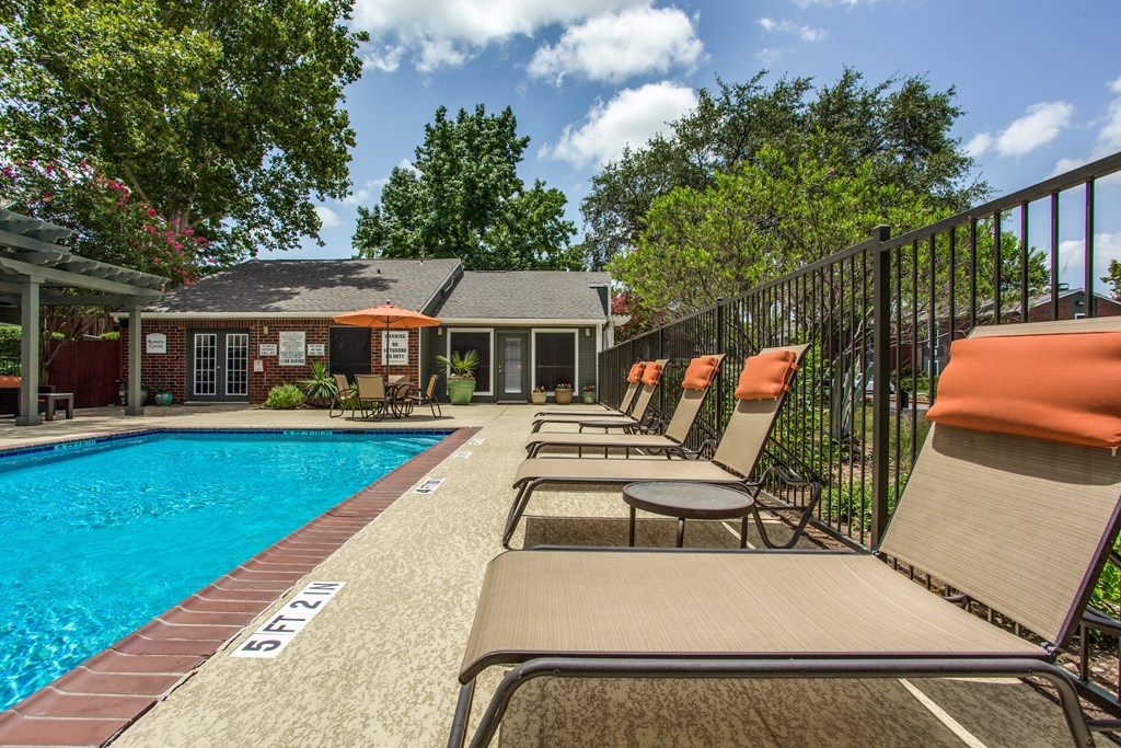 a pool with chairs and a house in the background