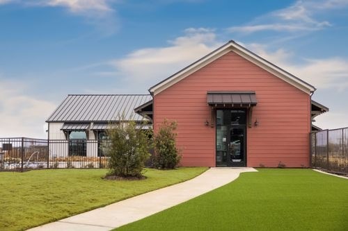 A red building with a black door and windows at Lockhart Farms Apartments, Lockhart, TX