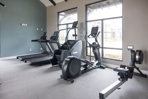 A gym with treadmills, elliptical machines, and a weight machine at Lockhart Farms Apartments, Lockhart, TX, 78644