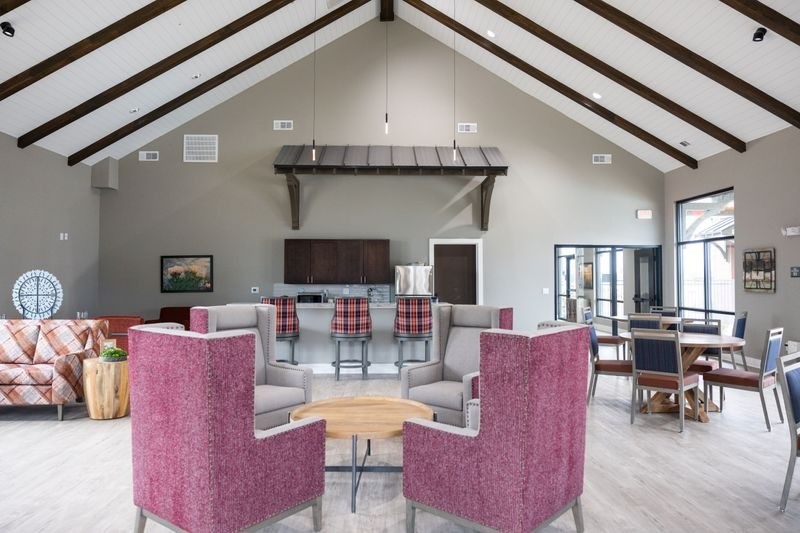 A room with a pink chair in the foreground and a couch in the background at Lockhart Farms Apartments, Lockhart, TX