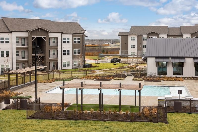 A large building with a pool in front of it at Lockhart Farms Apartments, Lockhart, Texas