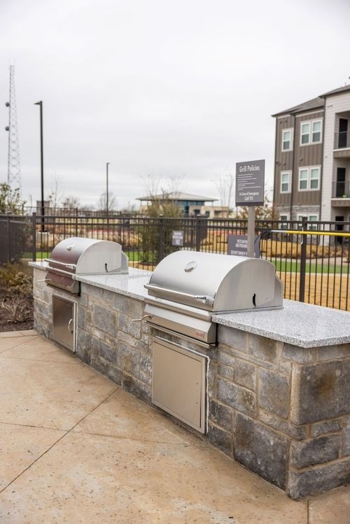 A stone wall with a mailbox and a grill on top at Lockhart Farms Apartments, Lockhart, TX, 78644