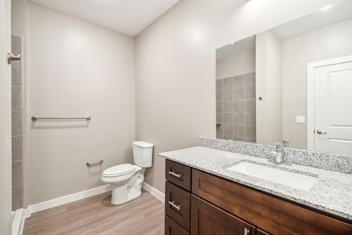 A bathroom with a toilet, sink, and mirror at Lockhart Farms Apartments, Lockhart, TX