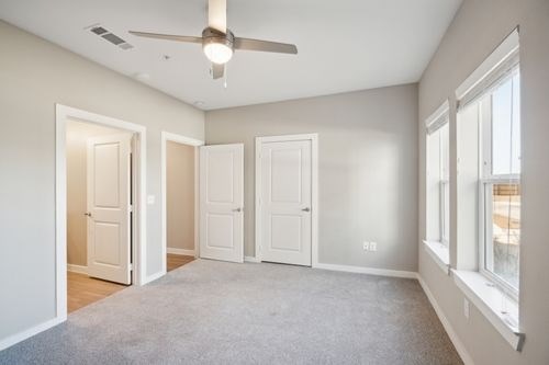 A room with a ceiling fan and three doors at Lockhart Farms Apartments, Texas