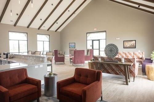 A living room with a red chair and a brown couch at Lockhart Farms Apartments, Lockhart, TX, 78644