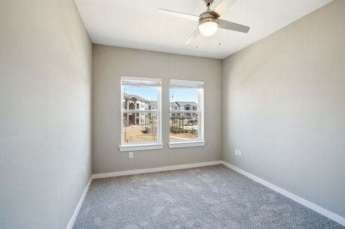 A room with a ceiling fan and two windows at Lockhart Farms Apartments, Texas, 78644