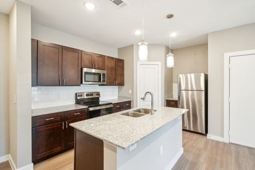 A kitchen with a white countertop and brown cabinets at Lockhart Farms Apartments, Texas, 78644