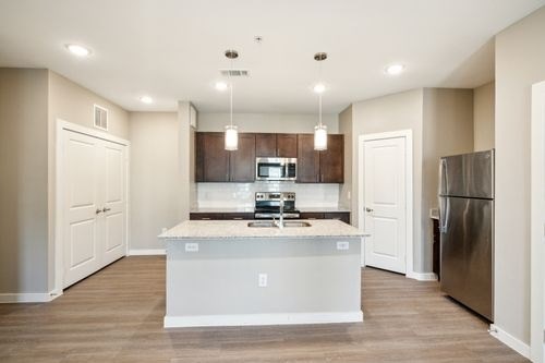 A kitchen with a white island and stainless steel appliances at Lockhart Farms Apartments, Texas
