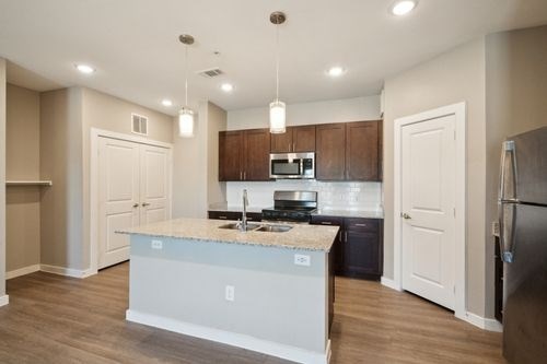 A kitchen with a white island and wooden cabinets at Lockhart Farms Apartments, Lockhart