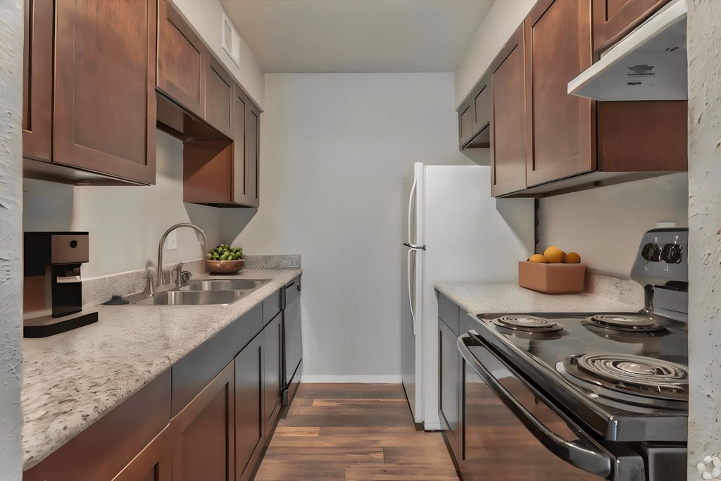 a kitchen with wooden cabinets and granite counter tops and a stainless steel stove and refrigerator
