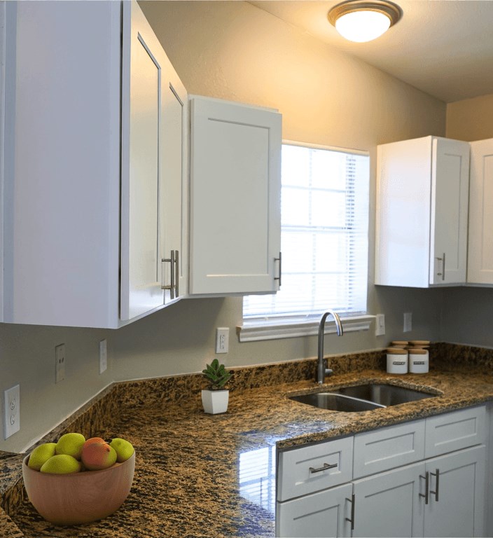a kitchen with white cabinets and a granite counter top and a sink
