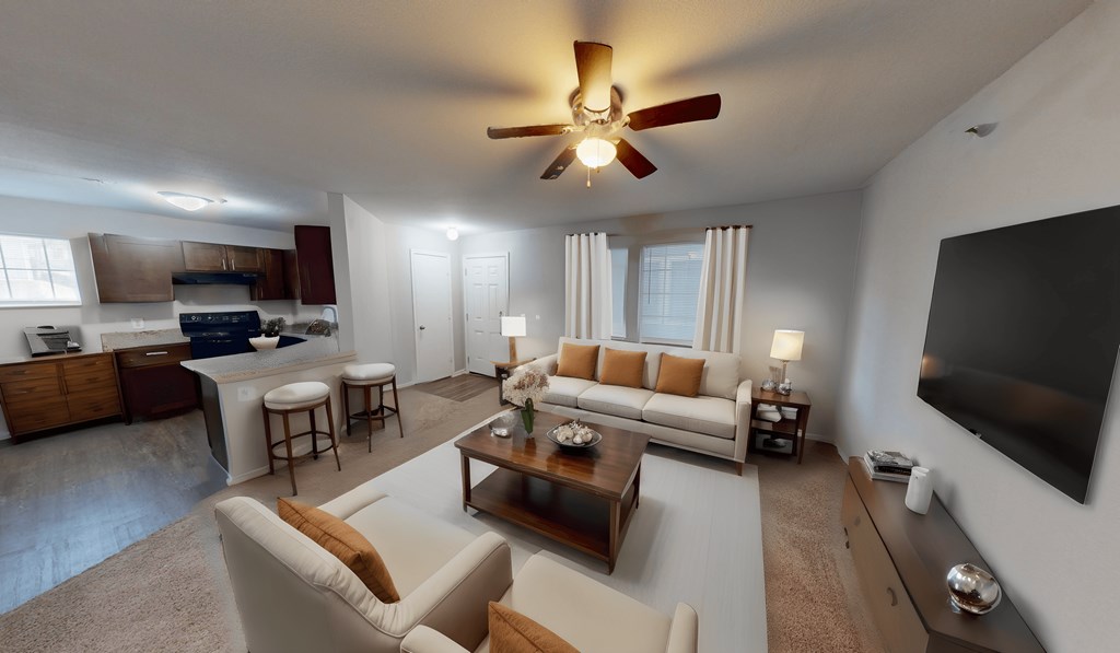 living room with couches and a large tv and a kitchen