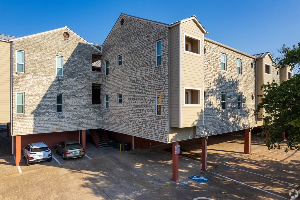 a building with a brick facade and a parking lot with cars