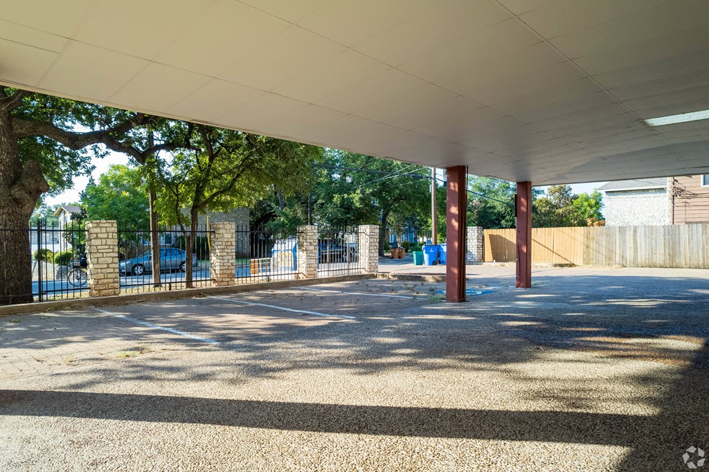 a covered parking lot with a fence and trees