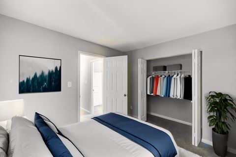 a bedroom with a bed and a closet with clothes