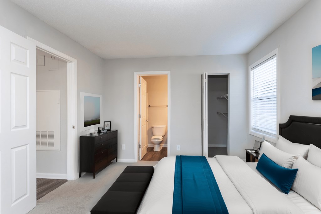 a bedroom with a large bed and a bathroom with a toilet