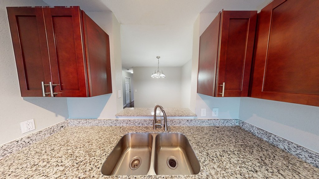 Kitchen sink with cabinets on each side looking into dining room