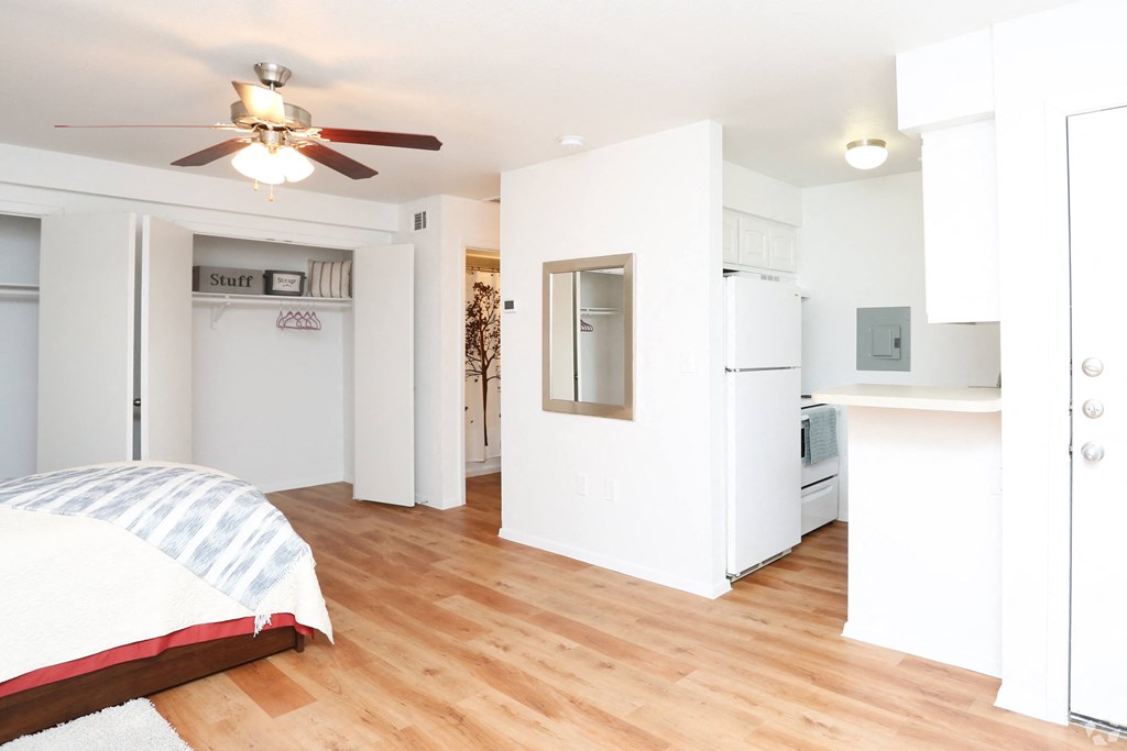 a bedroom with a bed and a kitchen with a ceiling fan