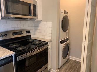 Stackable wash dryer next to kitchen at Triangle Park Apartments, North Carolina, 27713 - Photo Gallery 5