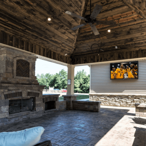 a covered patio with a fireplace and tv