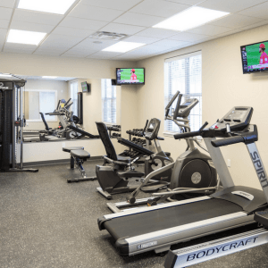 a room filled with lots of cardio equipment and a flat screen tv