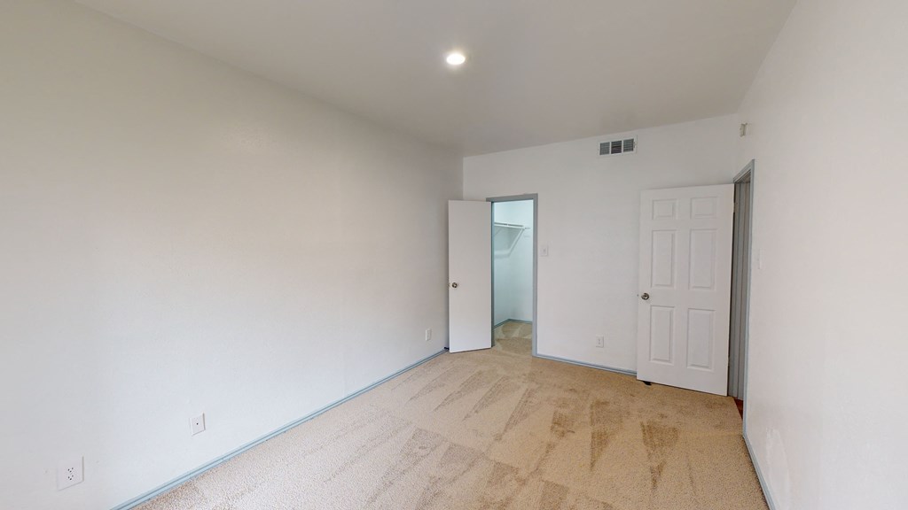 a living room with white walls and a door to a hallway