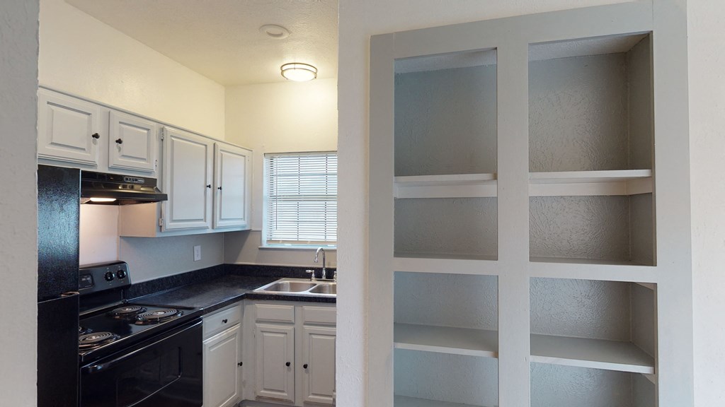 A kitchen with black appliances and white cabinets.