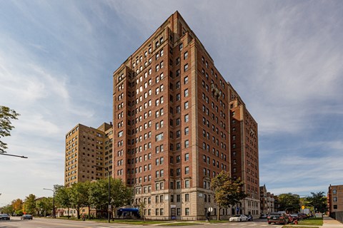 A large red brick building stands in the middle of a street.