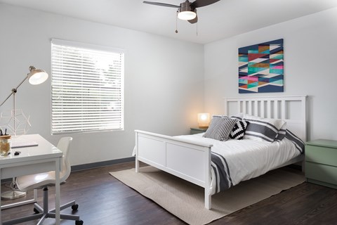 A bedroom with a bed, desk, and chair.