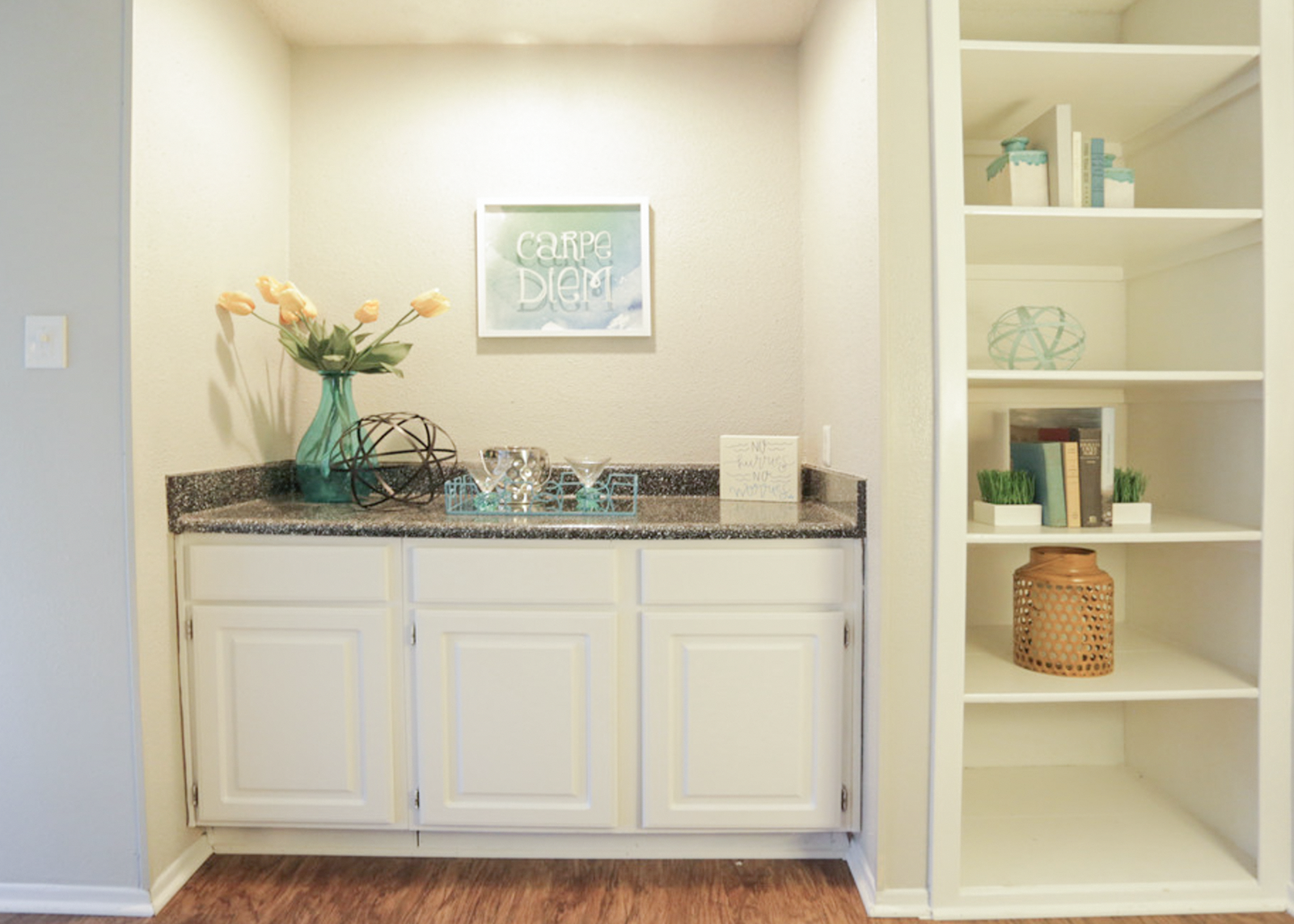 A kitchen with a white cabinet and a framed poster on the wall.