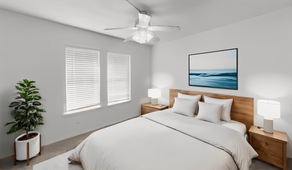 a white bedroom with a large bed and a ceiling fan
