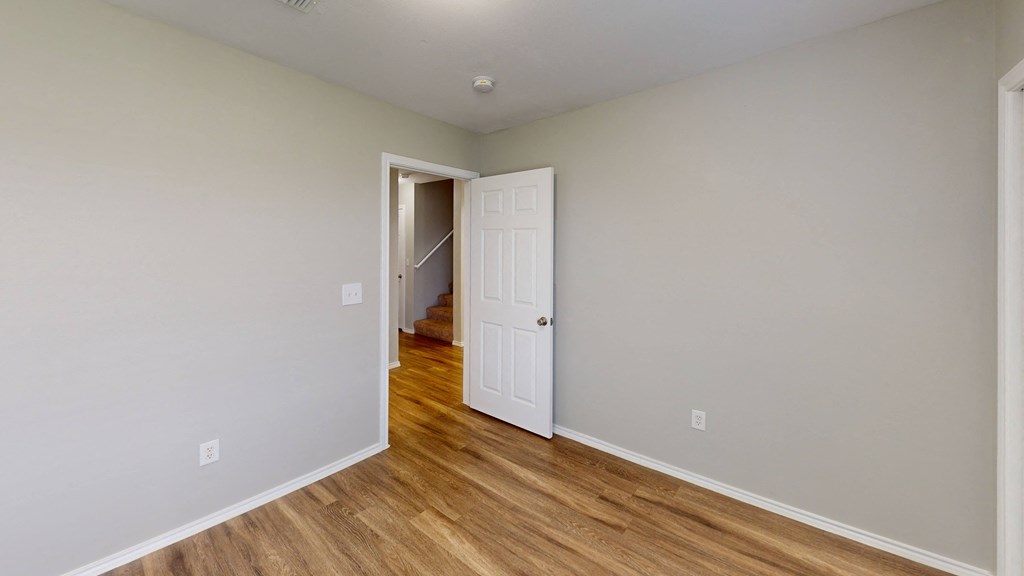 an empty room with wood floors and a white door