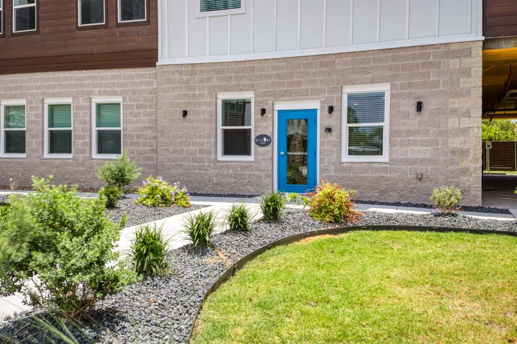 a blue door on a brick building with a lawn and plants