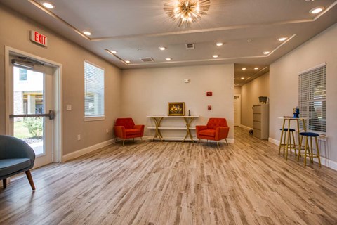 a living room with red chairs and a table and a door