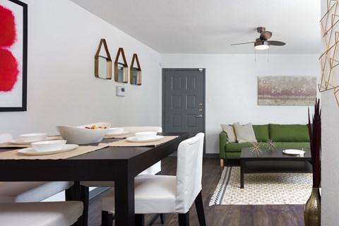 A dining room with a table set for two and a green couch.