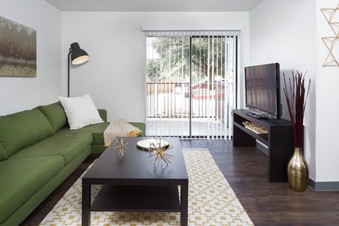 A living room with a green couch and a black coffee table.