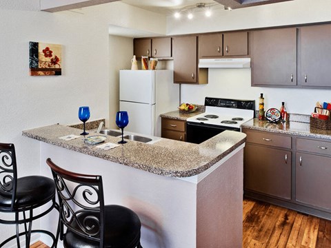 A kitchen with a white fridge and a granite counter top.