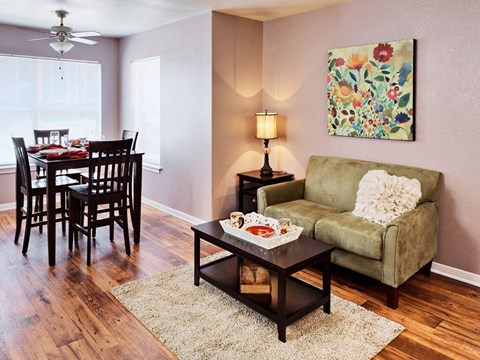 A living room with a dining table, chairs, a couch, a coffee table, and a painting on the wall.