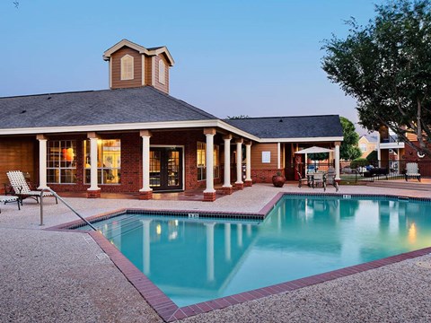 Evening view of pool with brick clubhouse at Country Oaks Apartments, San Marcos, TX 78666