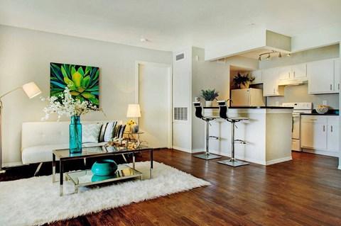 A modern living room with a white sofa and a coffee table with a blue vase on it.