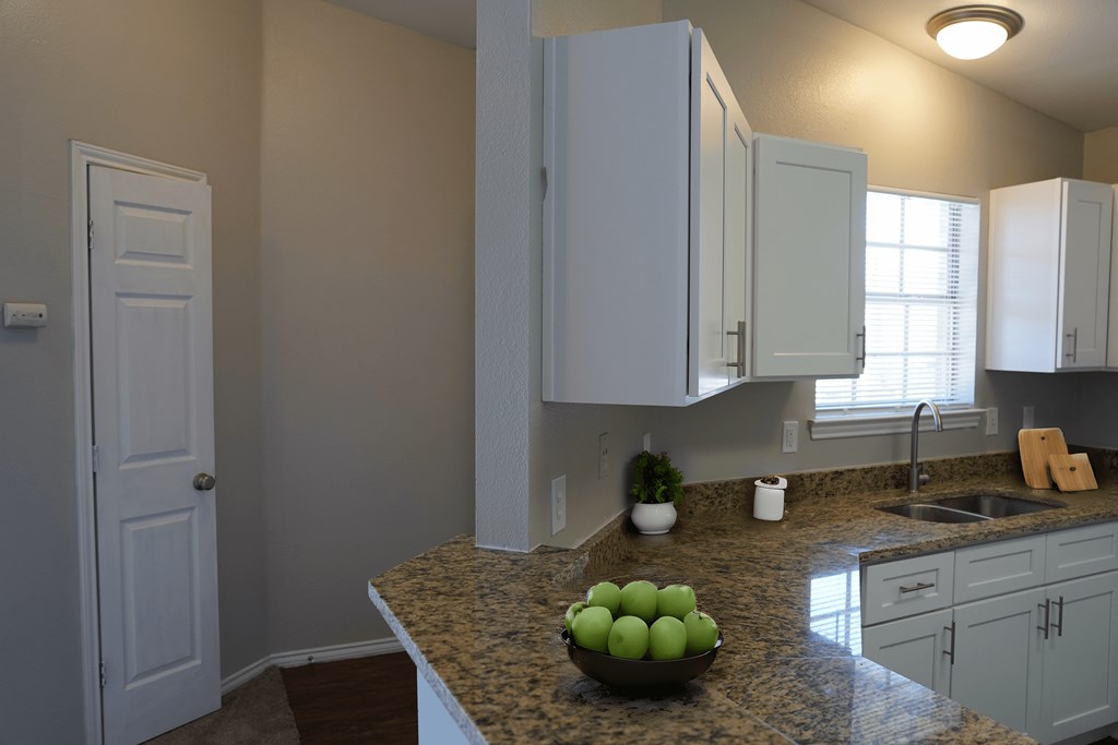 a kitchen with white cabinets and a bowl of fruit on the counter