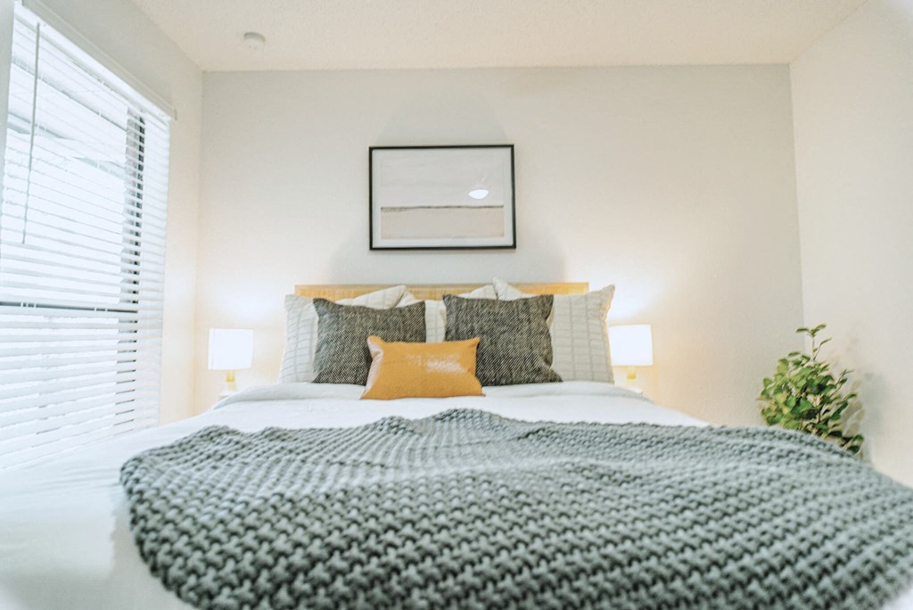 a bedroom with a bed with a gray blanket and pillows