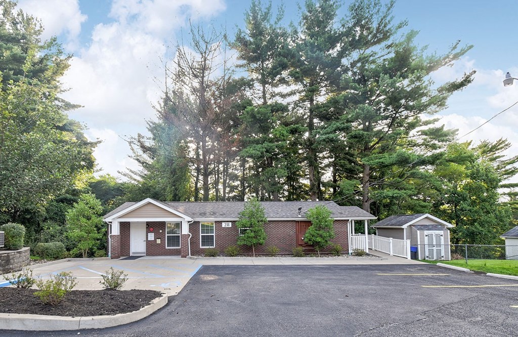 A parking lot with a building and a fence in the background.