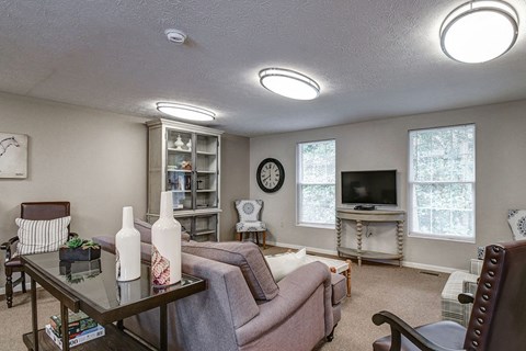 A living room with a couch, chair, and a table with two vases on it.