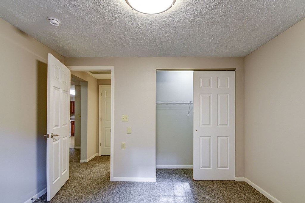 A hallway with a white door on the right and a brown door on the left.