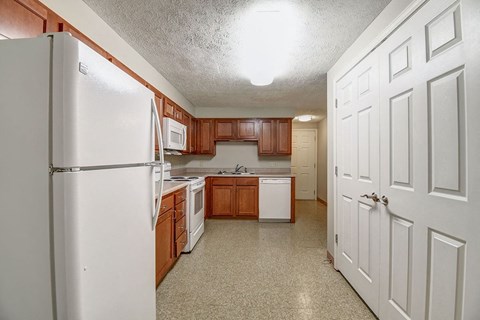A kitchen with a white refrigerator and brown cabinets.