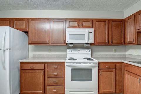 A kitchen with a white stove top oven and white microwave above it.