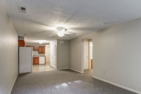 A spacious room with a refrigerator and a ceiling fan.