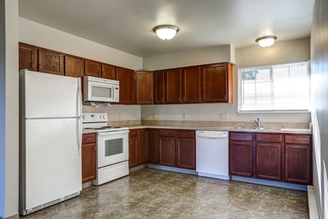 an empty kitchen with white appliances and wooden cabinets
