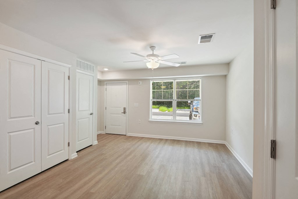 an empty living room with a ceiling fan and a window